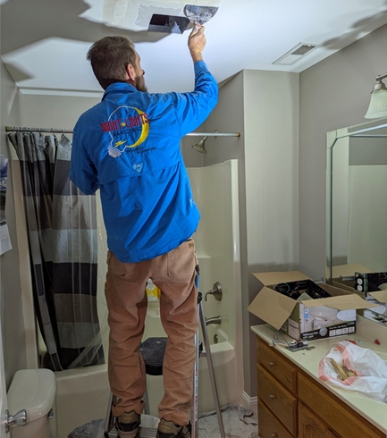 NightLightsElectric.com Stephen installing a new fan in a residential house bathroom. He is mudding in the new drywall opening.