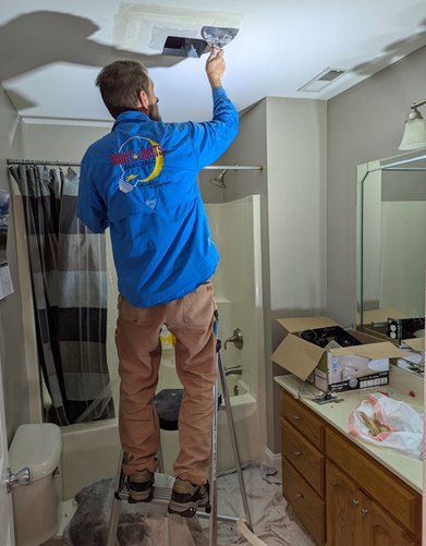 NightLightsElectric.com Stephen working on installing a new fan in a bathroom. He is mudding in the new drywall opening.